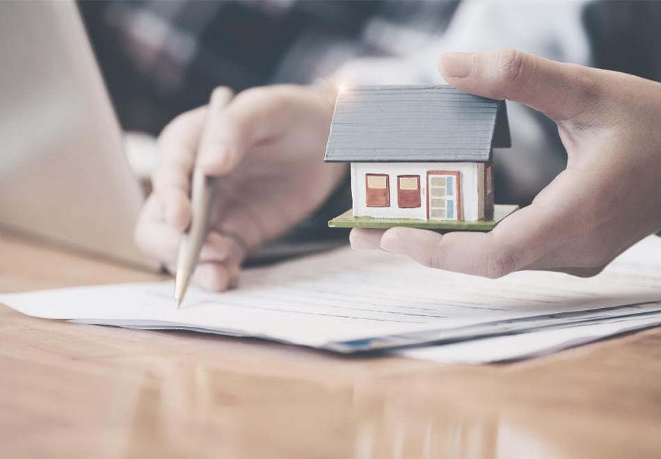 someone taking notes, holding a miniature house in other hand